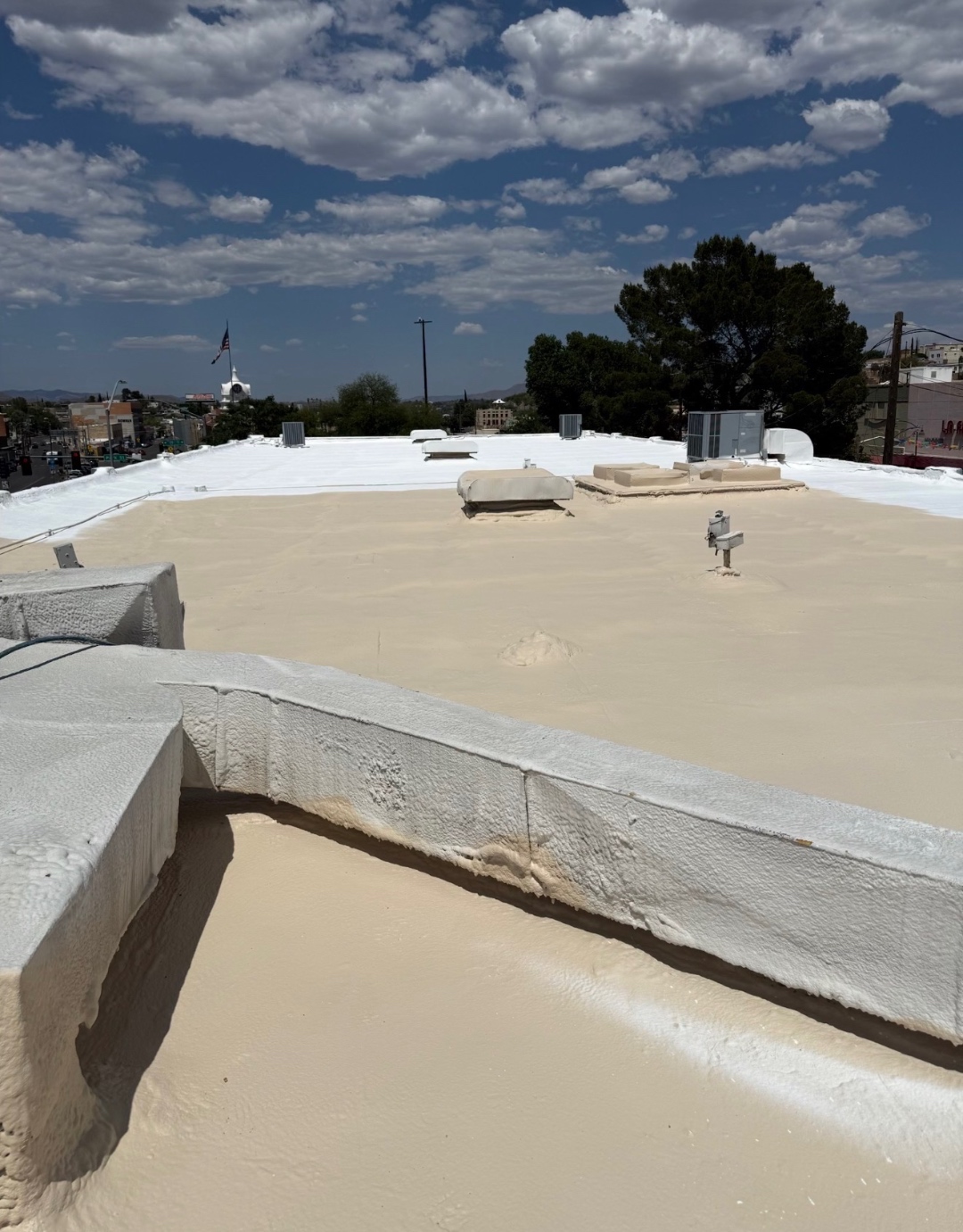 Tan primer applied during a W&D Roofing flat roof coating project