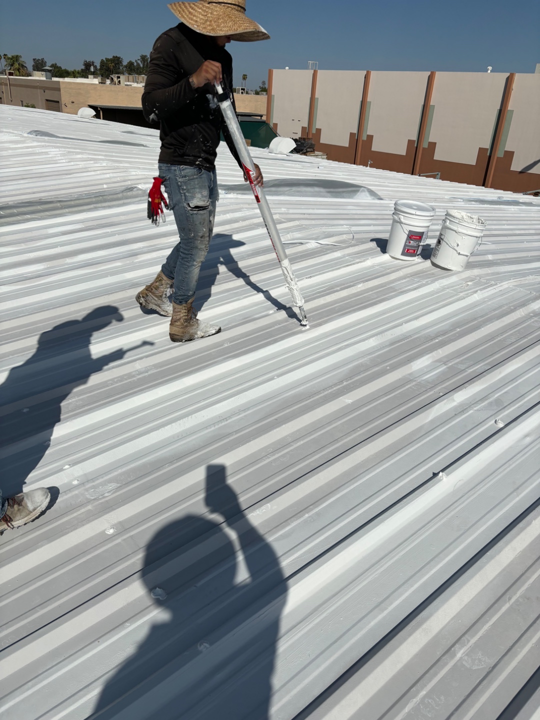 W&D Roofing applying commercial white roof coating with coating gun