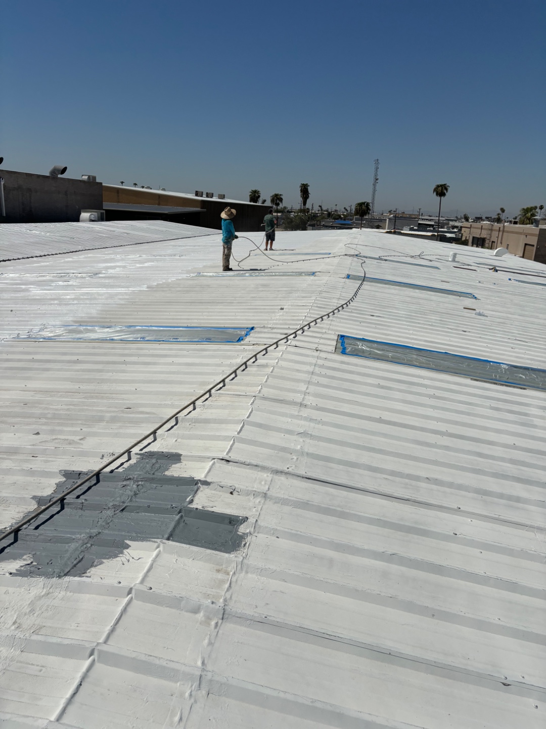 Commercial roof coating crew working on a reflective roof system