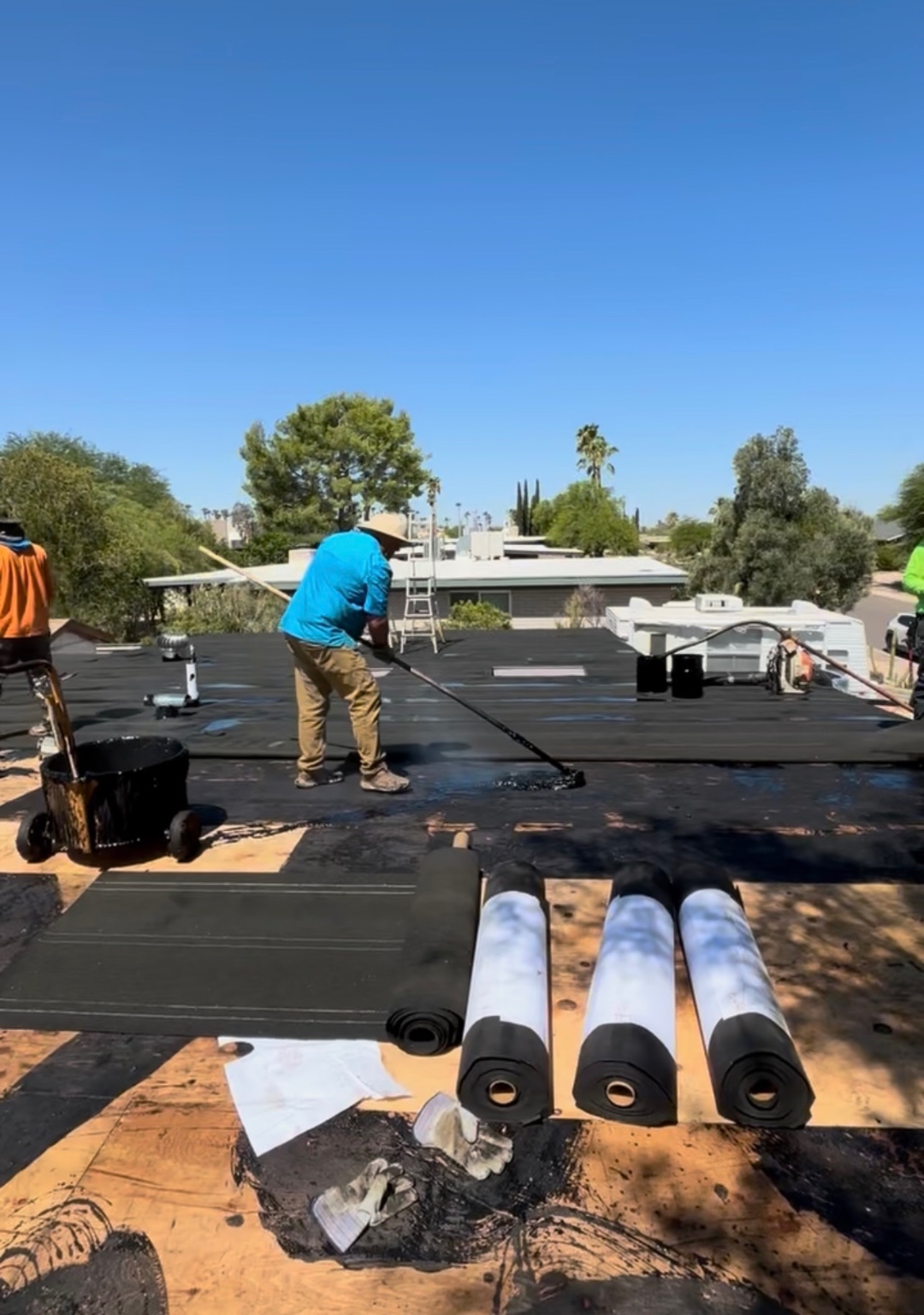W&D Roofing crew installing built-up roofing material on a flat roof