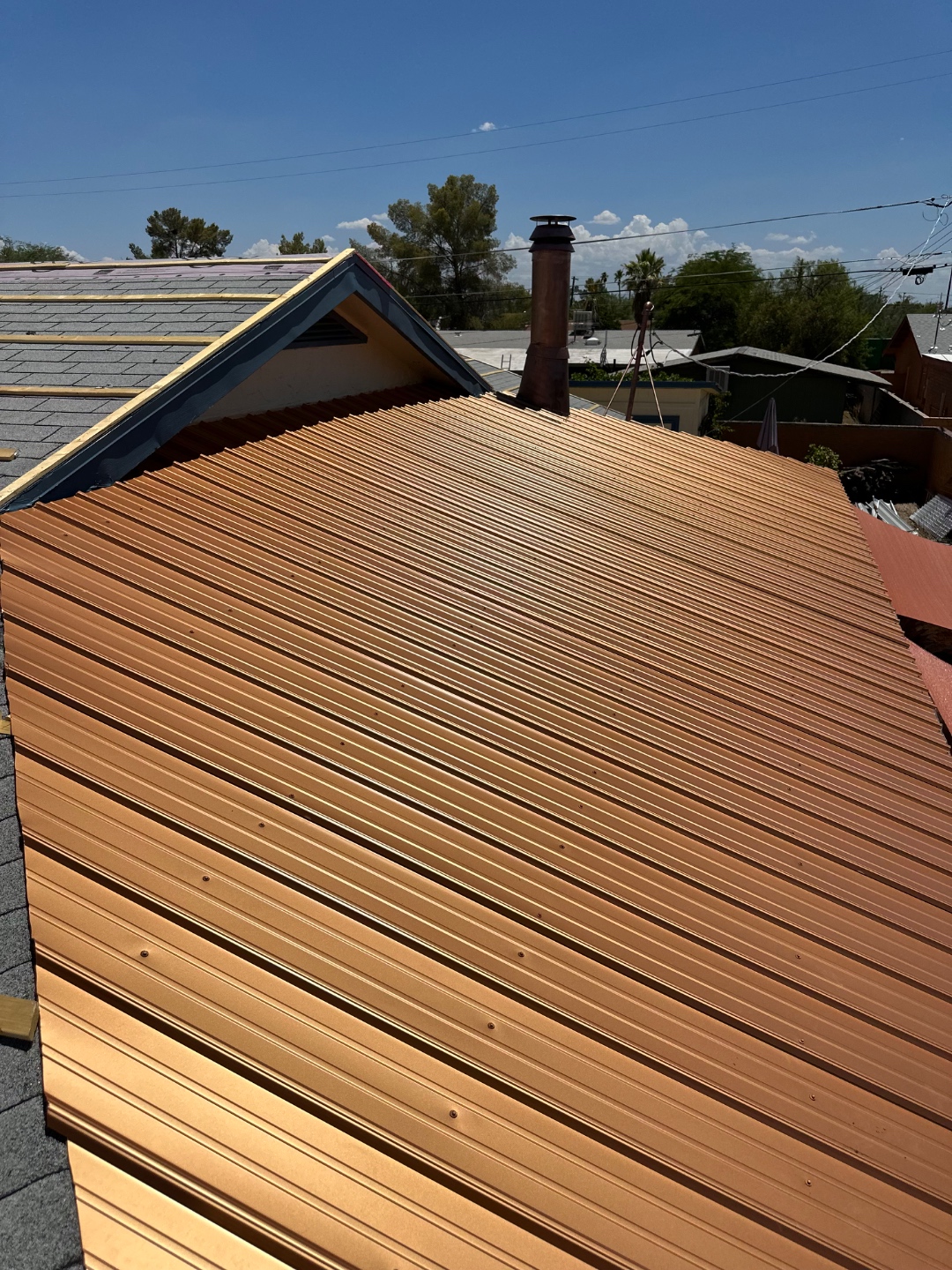 Metal roofing installation progress showing bronze metal panels and roof work